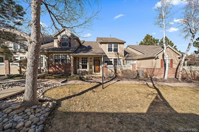 view of front facade with brick siding, fence, and a front lawn