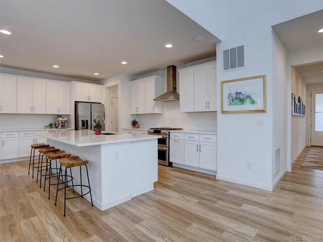 11246 Bellsong Ln, Littleton, CO 80125 - kitchen featuring wall chimney exhaust hood, stainless steel appliances, light wood-type flooring, backsplash, and recessed lighting