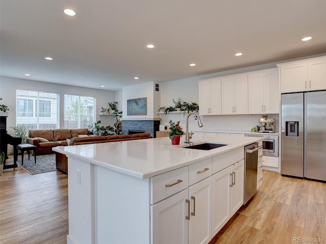 11246 Bellsong Ln, Littleton, CO 80125 - kitchen featuring stainless steel appliances, a fireplace, light wood-style flooring, light countertops, and recessed lighting