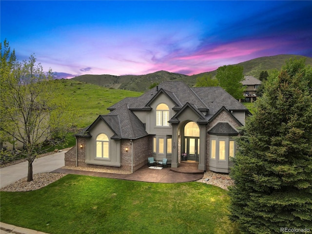 10 Summit Ash, Littleton, CO 80127 - french country style house with a mountain view, a lawn, roof with shingles, and stucco siding