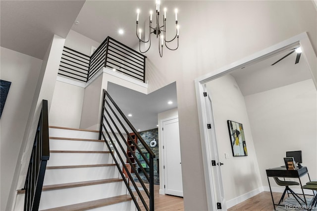 10 Summit Ash, Littleton, CO 80127 - staircase featuring wood finished floors, a towering ceiling, a chandelier, and baseboards