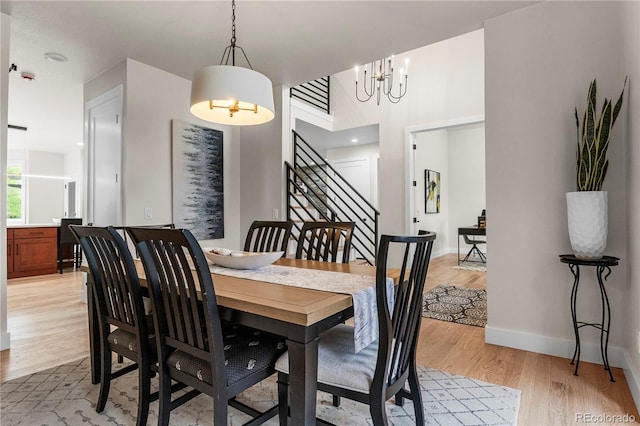 10 Summit Ash, Littleton, CO 80127 - dining space featuring a chandelier, light wood-style floors, stairway, a towering ceiling, and baseboards