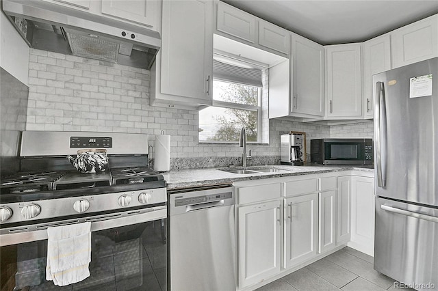 kitchen featuring a sink, light stone counters, under cabinet range hood, stainless steel appliances, and white cabinetry