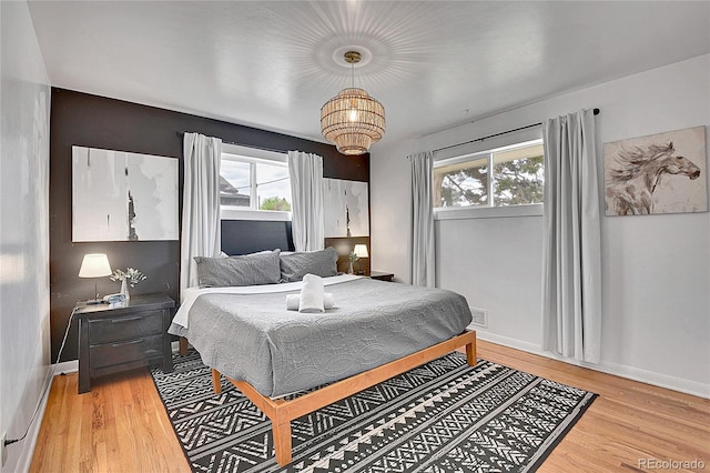 bedroom featuring an inviting chandelier, baseboards, light wood-style flooring, and visible vents