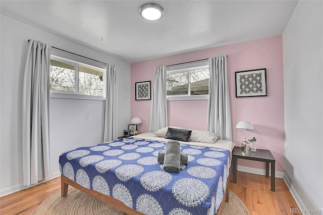 bedroom with baseboards, multiple windows, and light wood-style flooring