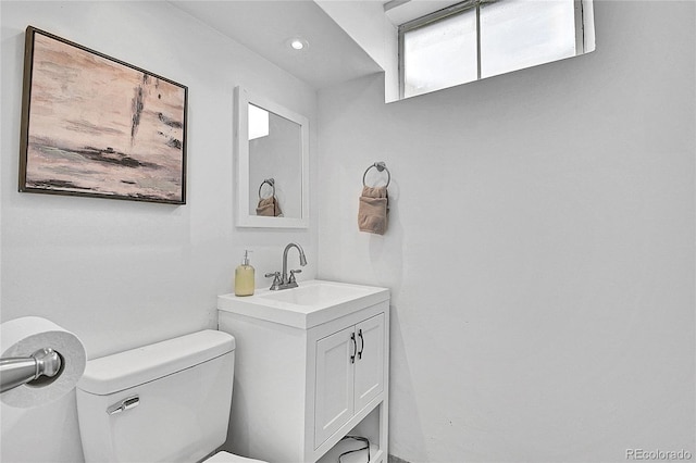 half bath with vanity, recessed lighting, and toilet