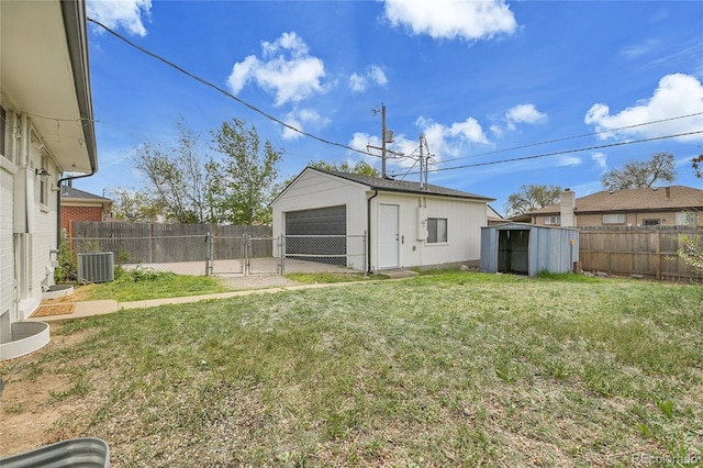 view of yard featuring a garage, central AC, a fenced backyard, a gate, and an outbuilding