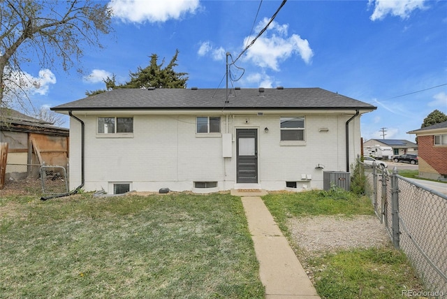 back of property featuring brick siding, a fenced backyard, roof with shingles, and a yard