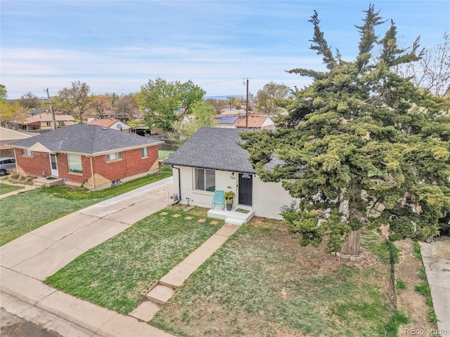 view of front of house with brick siding, driveway, a shingled roof, and a front yard