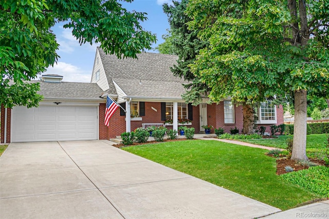 view of front of home featuring brick siding, a porch, a front yard, a garage, and driveway