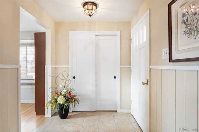 foyer entrance with light tile patterned floors and wainscoting