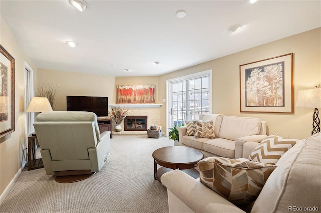 carpeted living room with a glass covered fireplace and baseboards