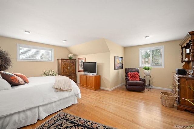 bedroom with vaulted ceiling, light wood-style floors, and baseboards