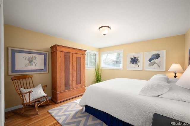 bedroom featuring light wood finished floors and baseboards