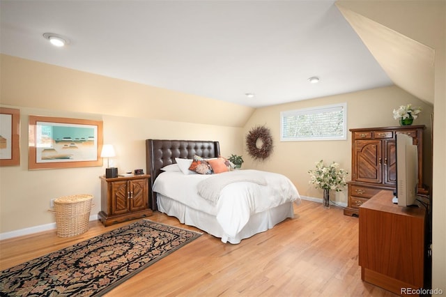 bedroom featuring baseboards, vaulted ceiling, and light wood finished floors