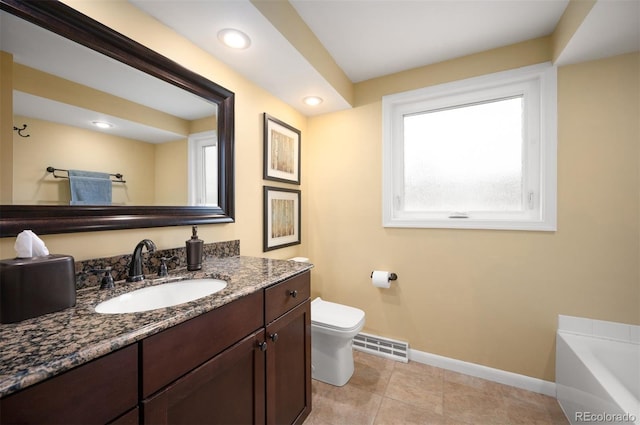 bathroom featuring vanity, baseboards, visible vents, a bathing tub, and toilet