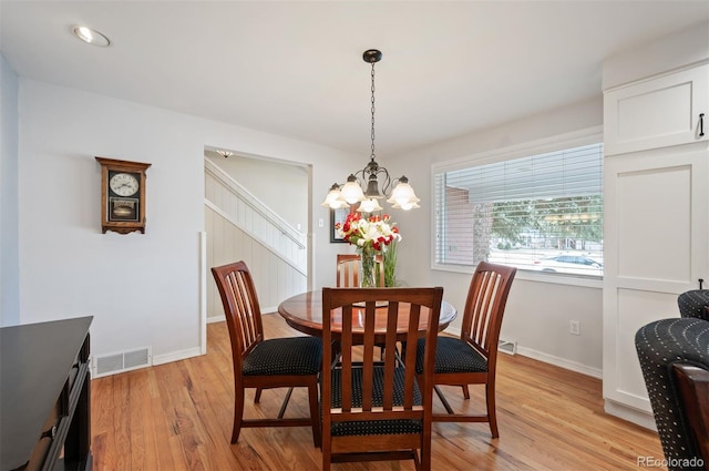 dining room featuring light wood finished floors, visible vents, baseboards, and an inviting chandelier