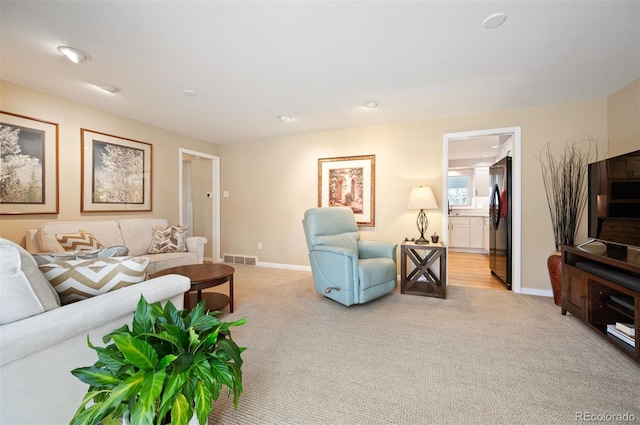 living area featuring visible vents, baseboards, and light colored carpet