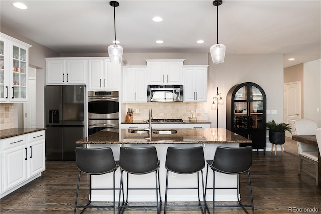 6236 S Millbrook Way, Aurora, CO 80016 - kitchen with appliances with stainless steel finishes, backsplash, recessed lighting, glass insert cabinets, and a kitchen bar