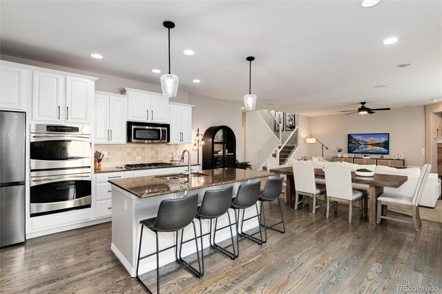 6236 S Millbrook Way, Aurora, CO 80016 - kitchen featuring stainless steel appliances, backsplash, dark wood-style flooring, recessed lighting, and a breakfast bar area