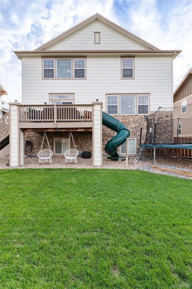 6236 S Millbrook Way, Aurora, CO 80016 - rear view of house featuring a trampoline, a wooden deck, a lawn, and a playground
