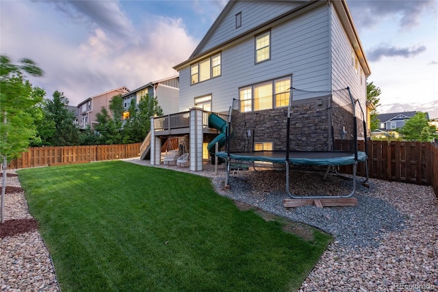 6236 S Millbrook Way, Aurora, CO 80016 - back of property with a trampoline, stairs, stone siding, a fenced backyard, and a deck