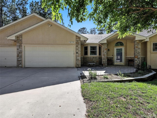 ranch-style home featuring stone siding, stucco siding, a garage, and concrete driveway