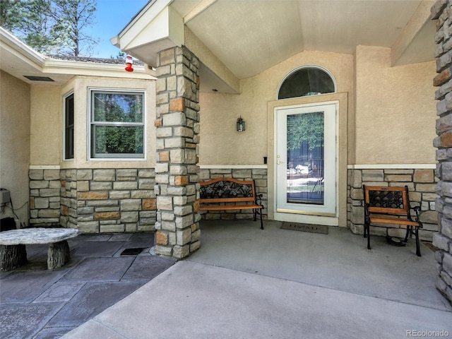 view of exterior entry with stone siding and stucco siding
