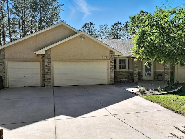 view of front facade featuring stone siding, a garage, driveway, and stucco siding