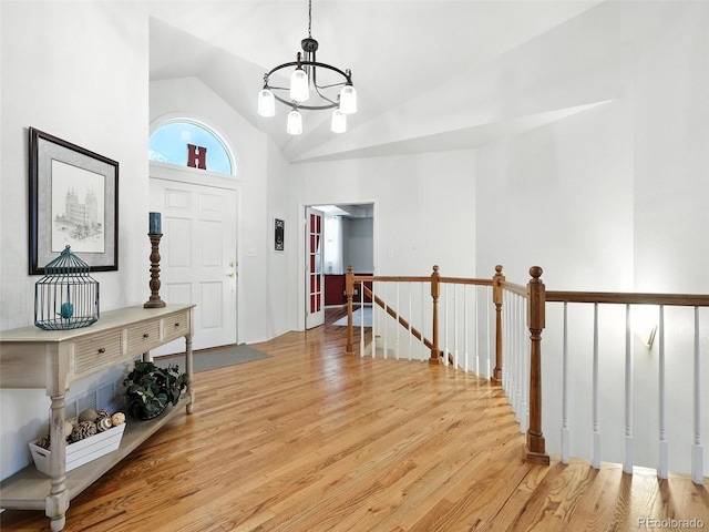 entrance foyer with a chandelier, wood finished floors, and high vaulted ceiling