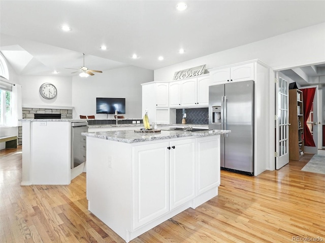 kitchen with stainless steel appliances, a center island, light wood-style floors, ceiling fan, and backsplash