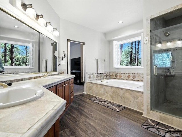 bathroom with wood finished floors, double vanity, a garden tub, a shower stall, and recessed lighting