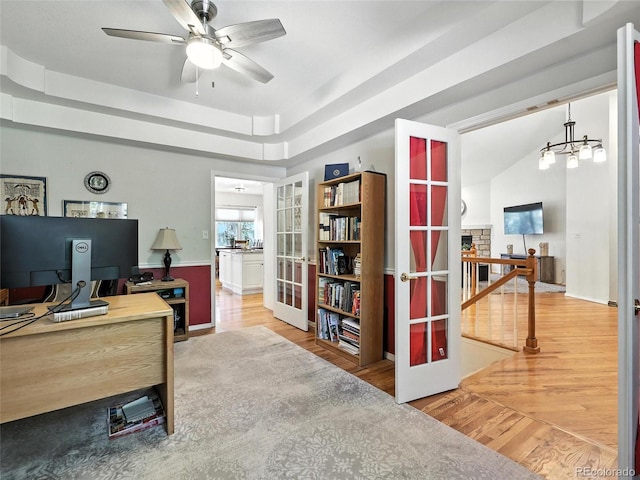 office with a ceiling fan, wood finished floors, french doors, and a raised ceiling