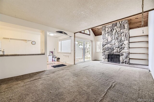2604 S Xanadu Way Unit B, Aurora, CO 80014 - unfurnished living room featuring carpet, lofted ceiling, a textured ceiling, and a fireplace