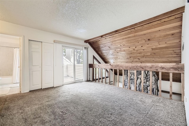 additional living space with carpet, vaulted ceiling, and a textured ceiling