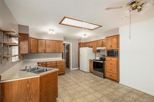 kitchen with brick wall, appliances with stainless steel finishes, a skylight, sink, and kitchen peninsula