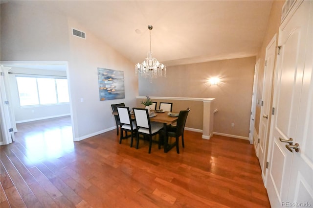 dining room featuring dark hardwood / wood-style floors, an inviting chandelier, and vaulted ceiling