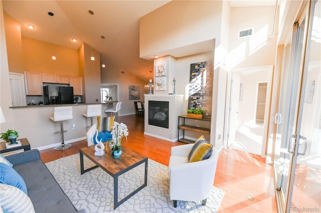 living room with light wood-type flooring and high vaulted ceiling