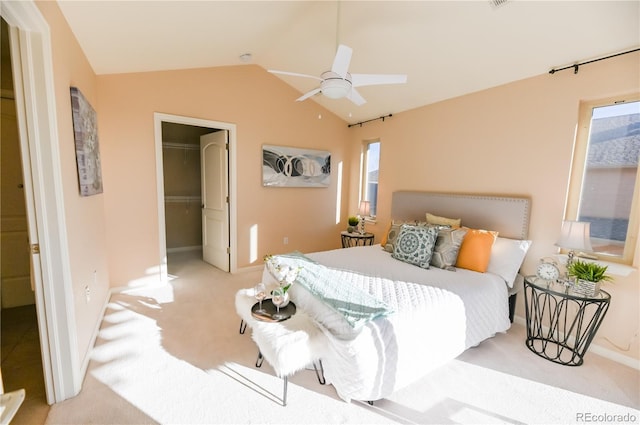 bedroom featuring ceiling fan, light carpet, vaulted ceiling, a closet, and a walk in closet