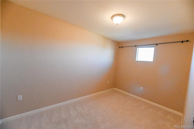 spare room featuring baseboards and light colored carpet