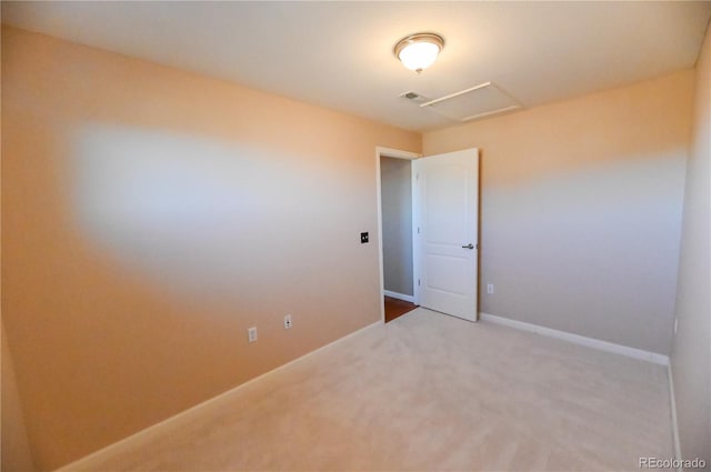 carpeted spare room with attic access, visible vents, and baseboards