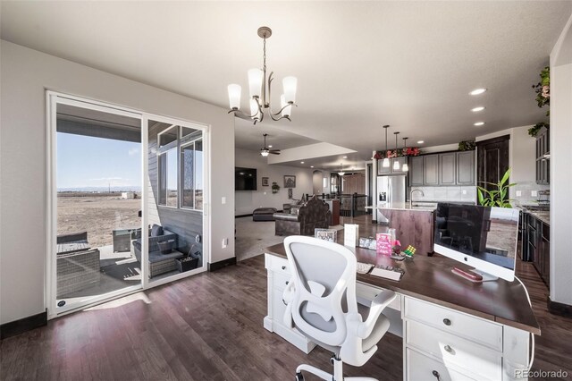 office area with dark hardwood / wood-style flooring, sink, and ceiling fan with notable chandelier