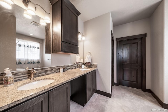 bathroom featuring tile patterned floors, vanity, decorative backsplash, and a textured ceiling