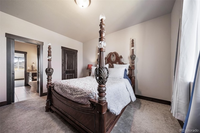 bedroom with ensuite bathroom and light carpet