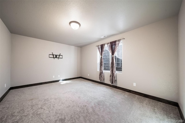 carpeted empty room featuring a textured ceiling