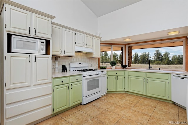 kitchen with tasteful backsplash, green cabinets, under cabinet range hood, white appliances, and a sink