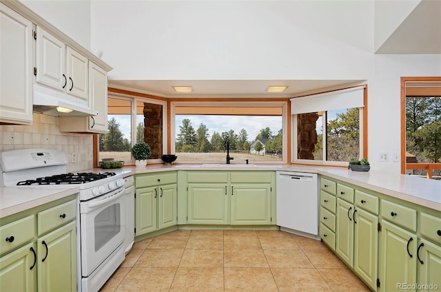 kitchen with under cabinet range hood, a sink, tasteful backsplash, white appliances, and light countertops