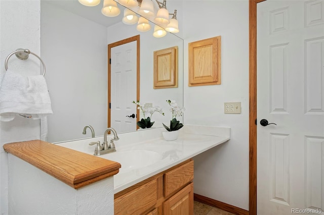 bathroom featuring a notable chandelier, vanity, and baseboards