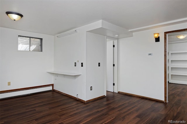 spare room featuring dark wood-style floors, baseboards, and a baseboard radiator