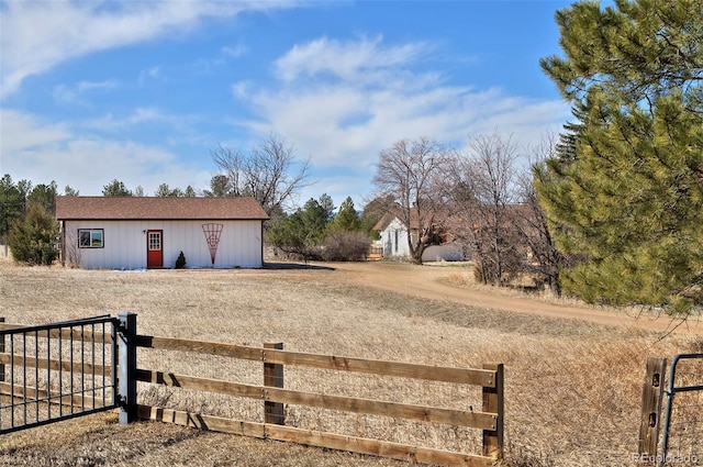 view of yard featuring a gate, an outbuilding, and fence